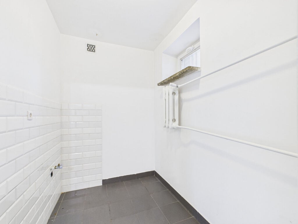 Pusta biała łazienka z suszarką ścienną