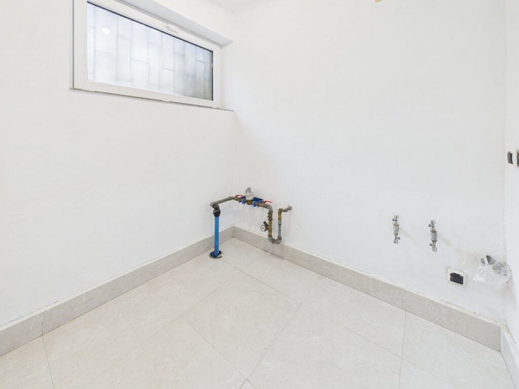 Pusta pralnia z przyłączami wodnymi i kafelkami