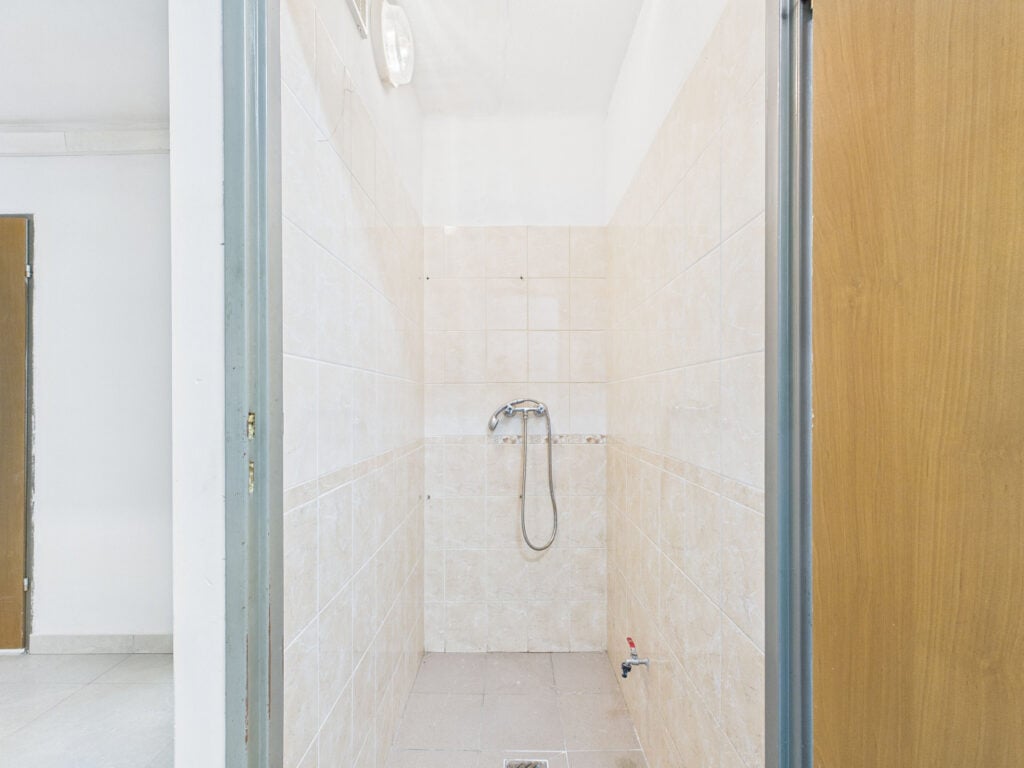 Prysznic w jasnym pomieszczeniu bez zasłony.