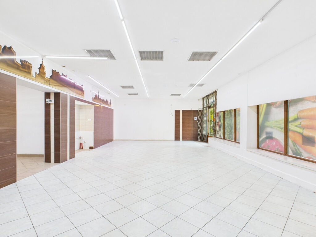 Wnętrze pustego sklepu z jasnym oświetleniem.