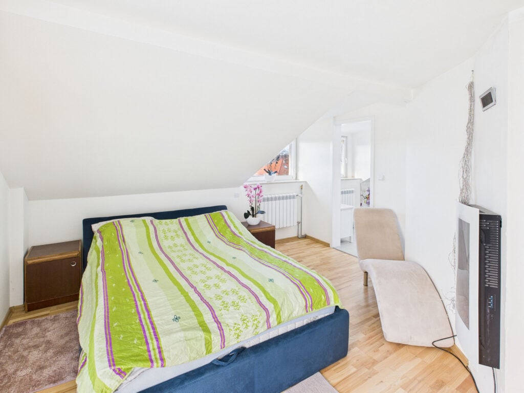 Sypialnia na poddaszu z łóżkiem i fotelem