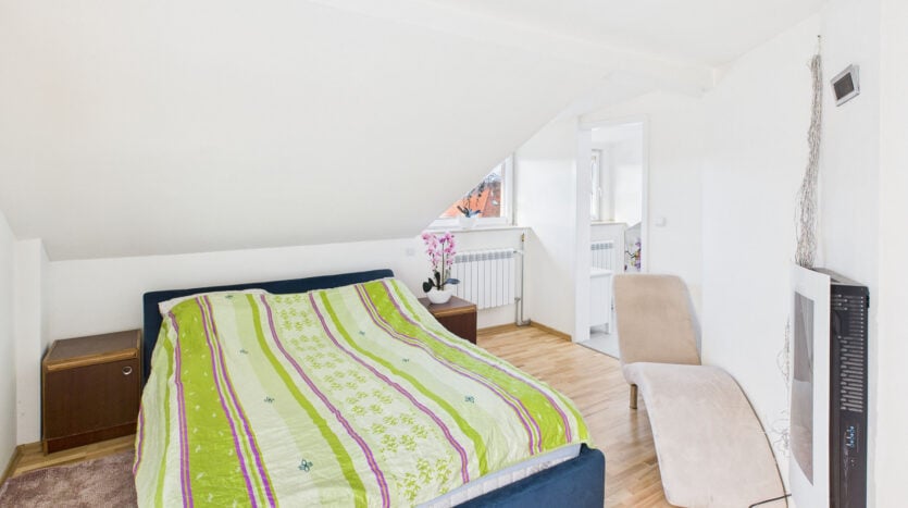 Sypialnia na poddaszu z łóżkiem i fotelem