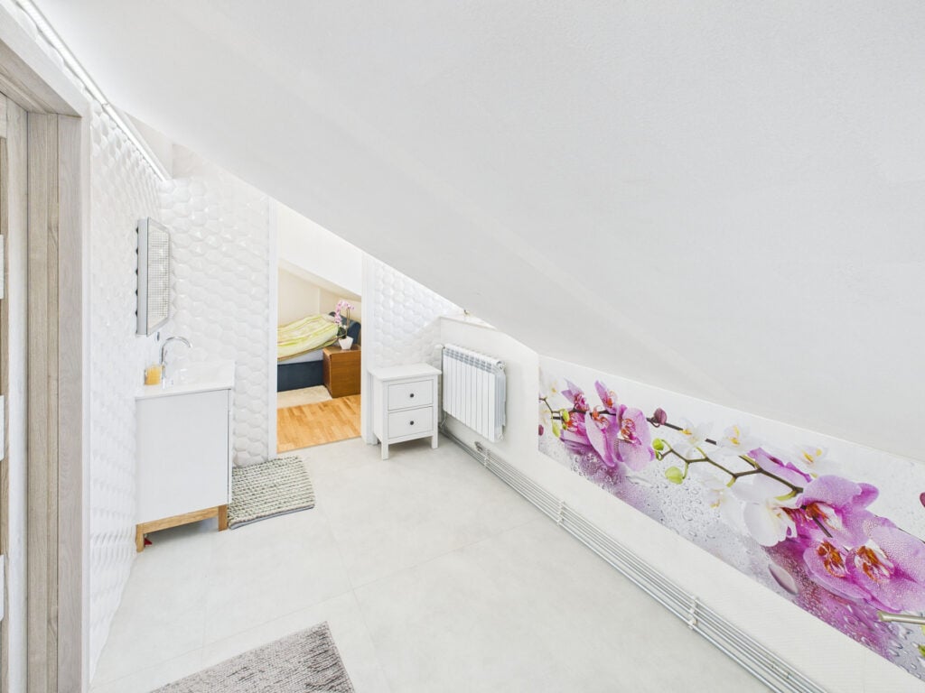 Jasna łazienka na poddaszu z motywem kwiatowym.