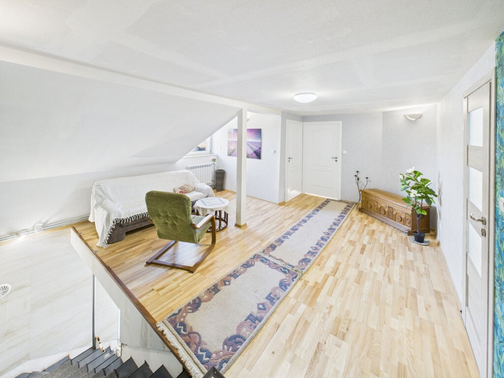 Jasne poddasze z sofą i fotelem, drewniana podłoga.