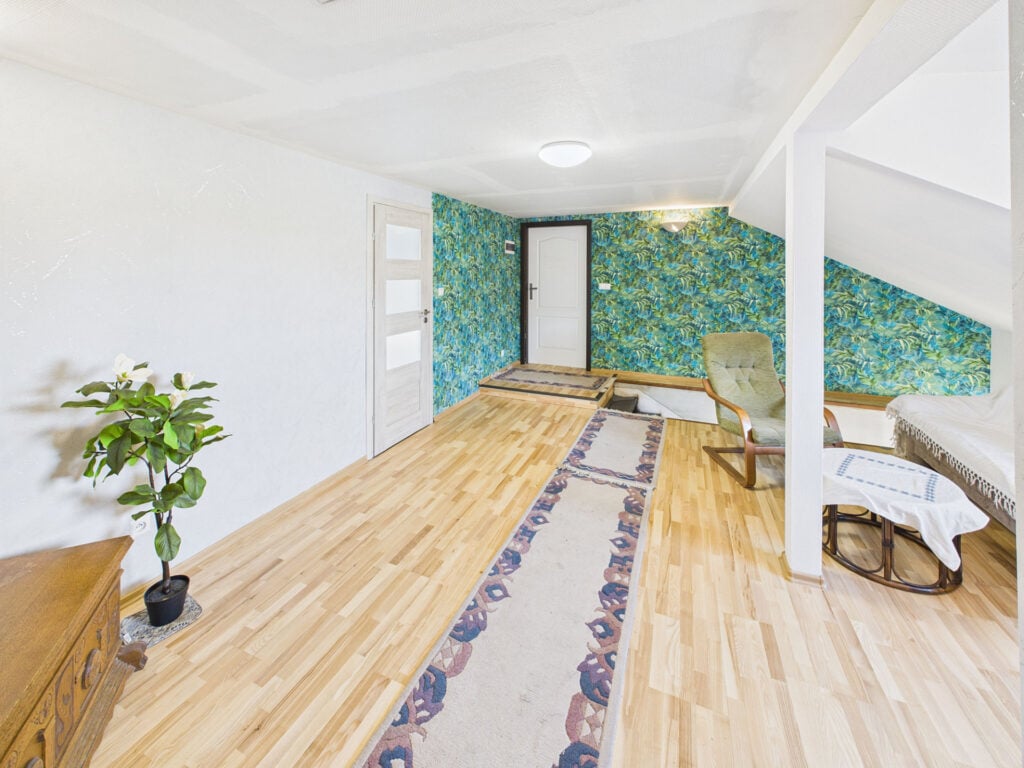 Przytulny pokój na poddaszu z roślinną tapetą.