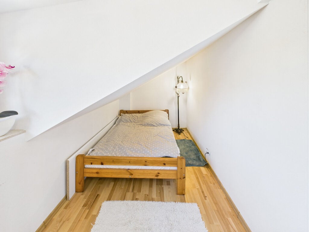 Mała sypialnia na poddaszu z drewnianym łóżkiem.