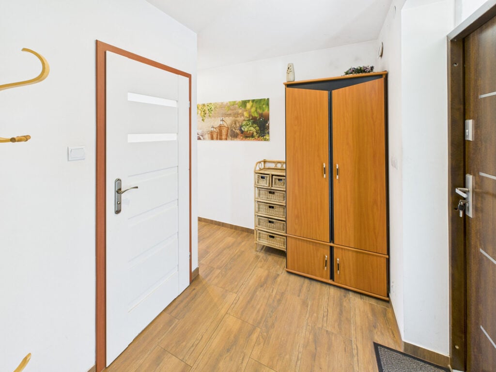 Przedpokój z szafą, drzwiami i drewnianą podłogą.