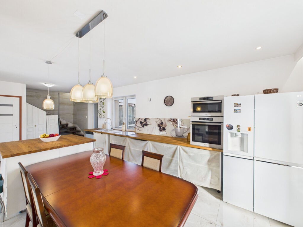 Nowoczesna kuchnia z drewnianym stołem i lampami.