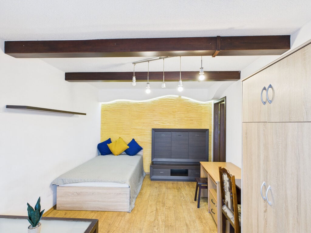 Przytulna sypialnia z drewnianymi meblami i rośliną.