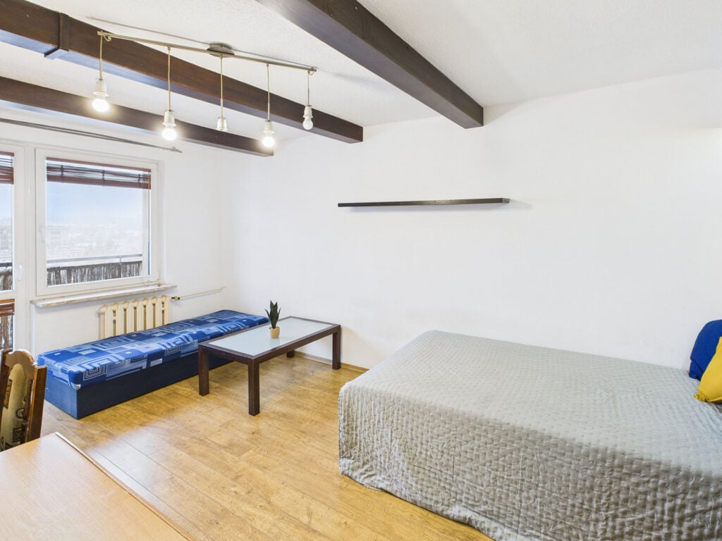 Jasny pokój z łóżkiem, stołem i kanapą.