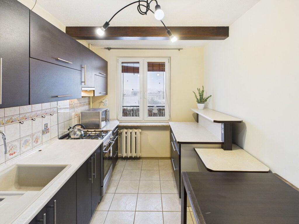 Nowoczesna kuchnia z ciemnymi szafkami i jasnymi blatami.