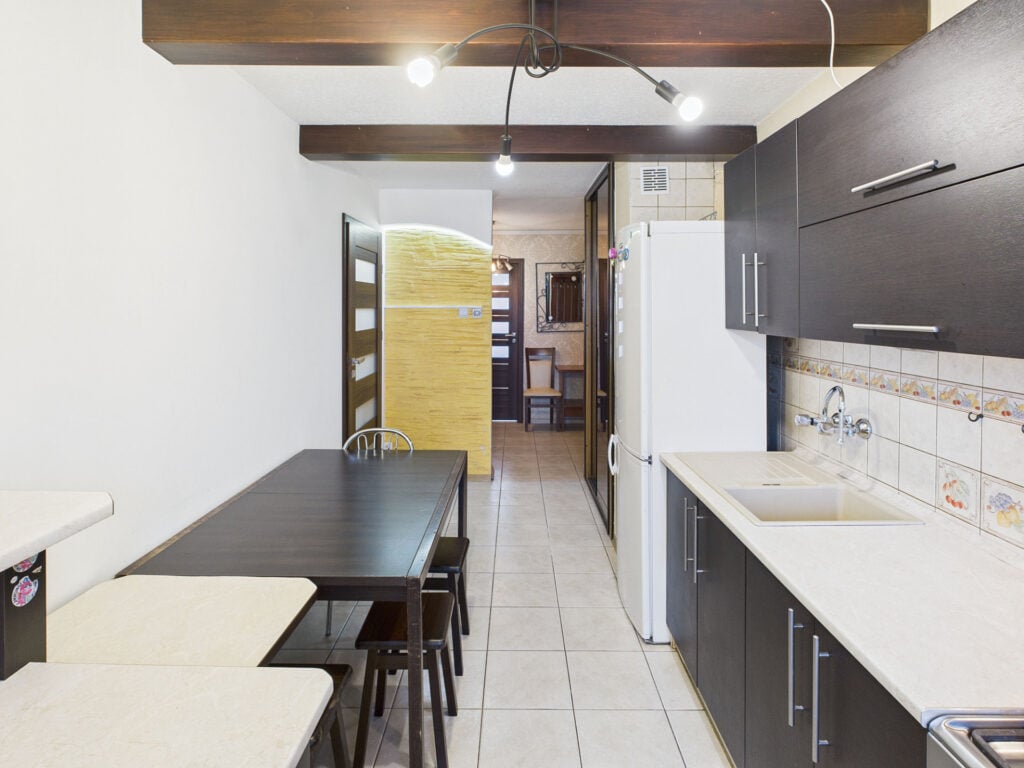 Nowoczesna kuchnia z ciemnymi meblami i stołem