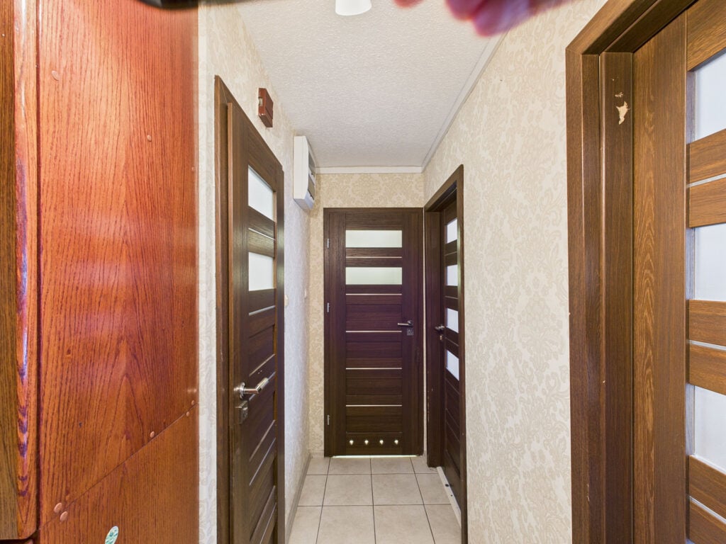 Korytarz z drewnianymi drzwiami i tapetą.