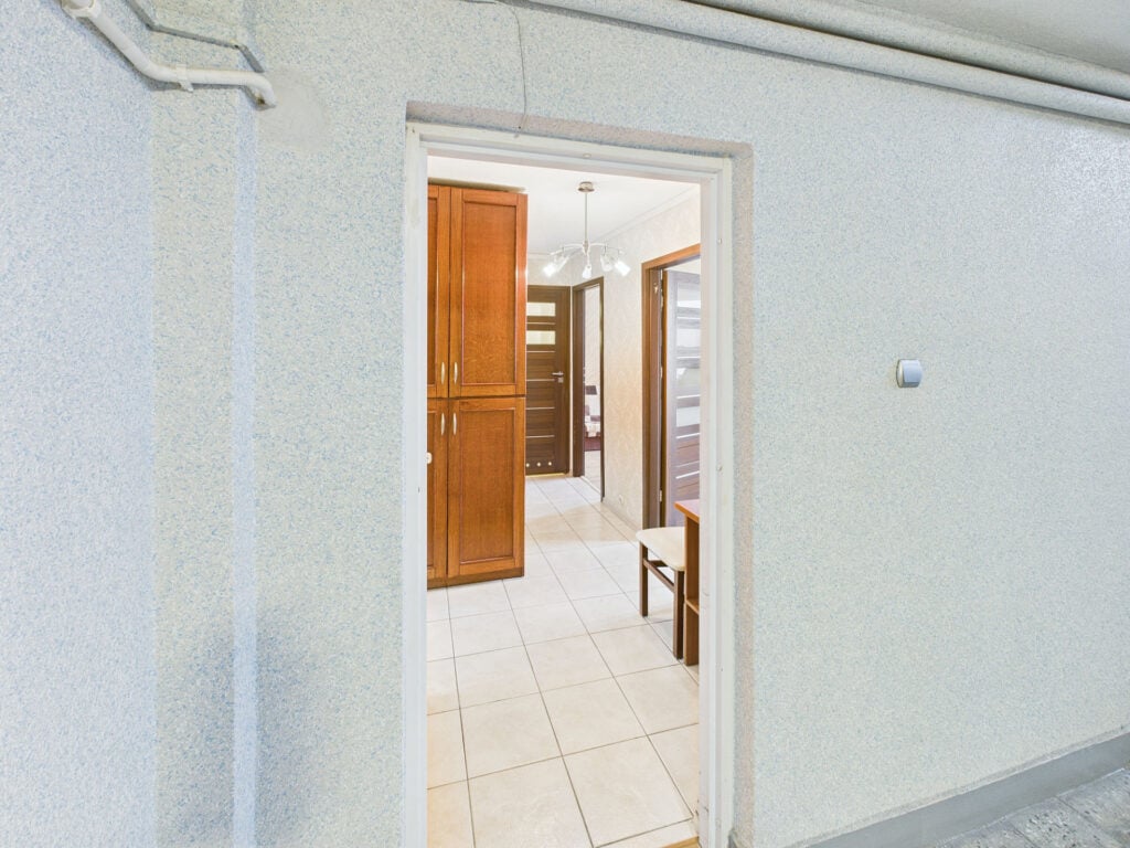 Przedsionek z szafką i jasno oświetlonym korytarzem.