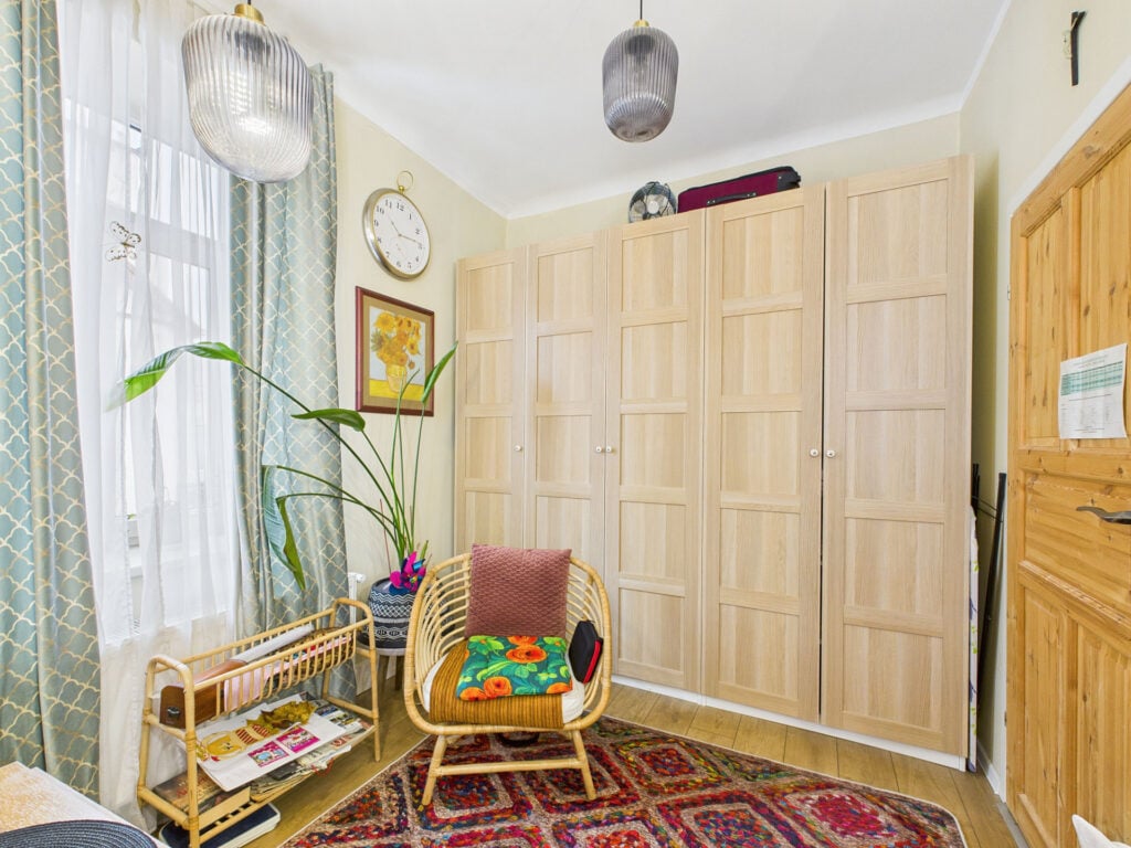 Pokój dzienny z szafą i wiklinowym fotelem.