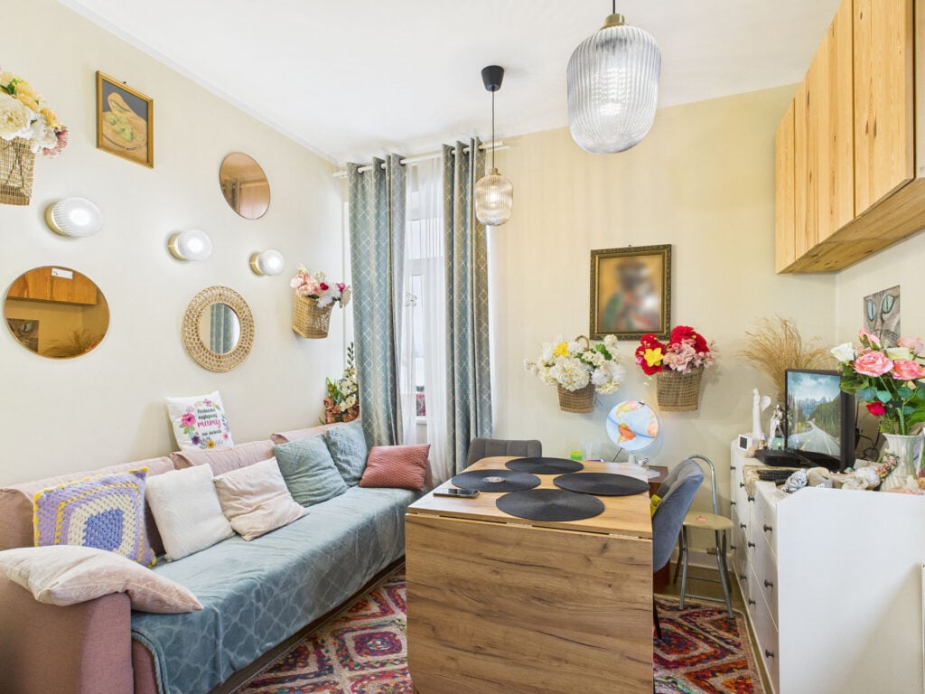 Przytulny salon z kwiatami i kolorowymi poduszkami.