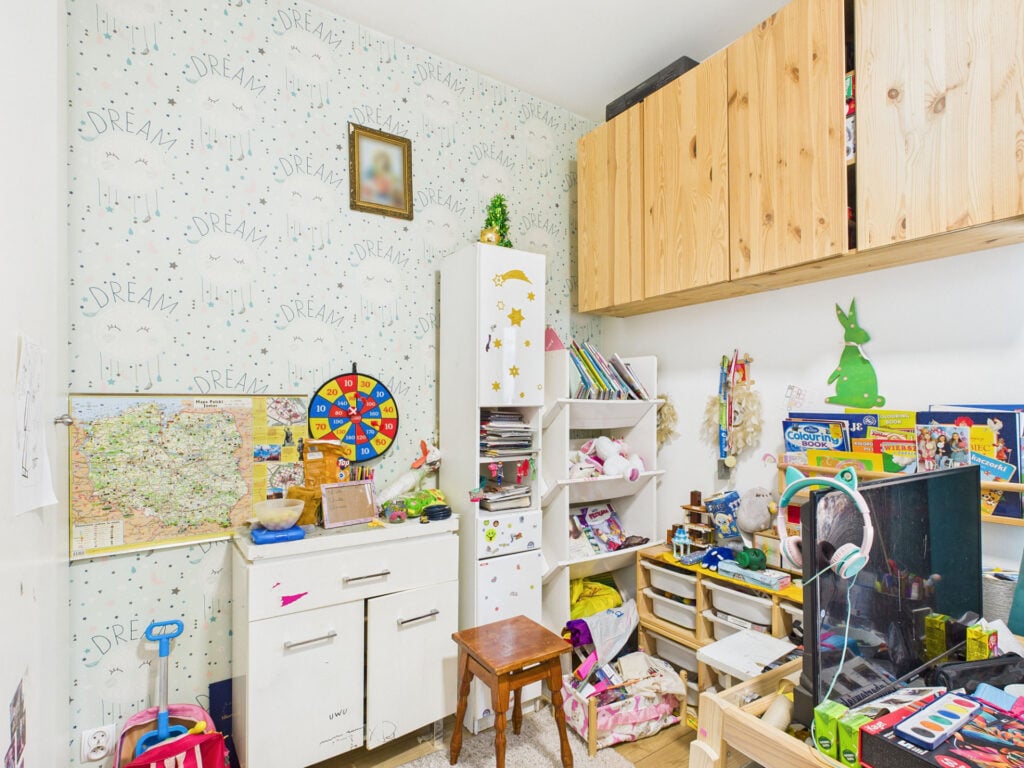 Pokój dziecięcy z zabawkami i szafkami na książki.