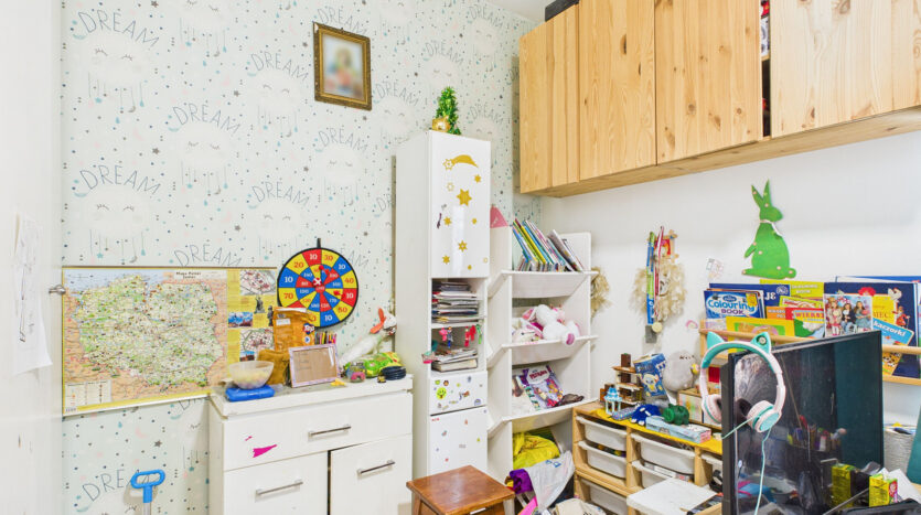 Pokój dziecięcy z zabawkami i szafkami na książki.