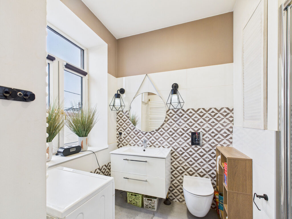 Nowoczesna łazienka z lustrem i wzorzystymi płytkami.