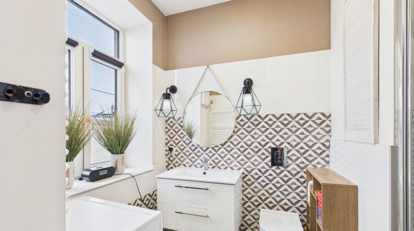 Nowoczesna łazienka z lustrem i wzorzystymi płytkami.