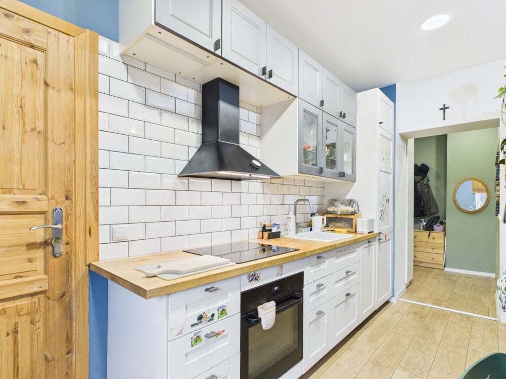 Nowoczesna kuchnia z białymi szafkami i drewnianymi blatami.