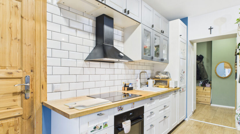 Nowoczesna kuchnia z białymi szafkami i drewnianymi blatami.