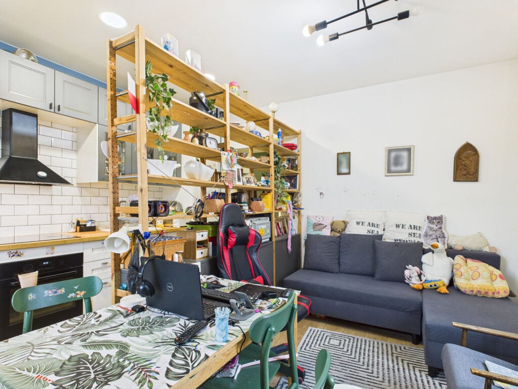 Nowoczesna kuchnia z salonem, zielony stół, szara kanapa.