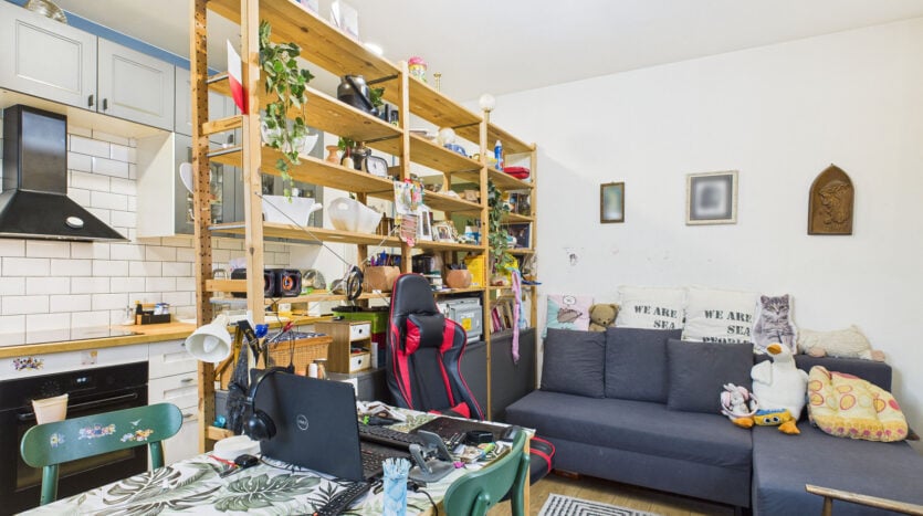 Nowoczesna kuchnia z salonem, zielony stół, szara kanapa.