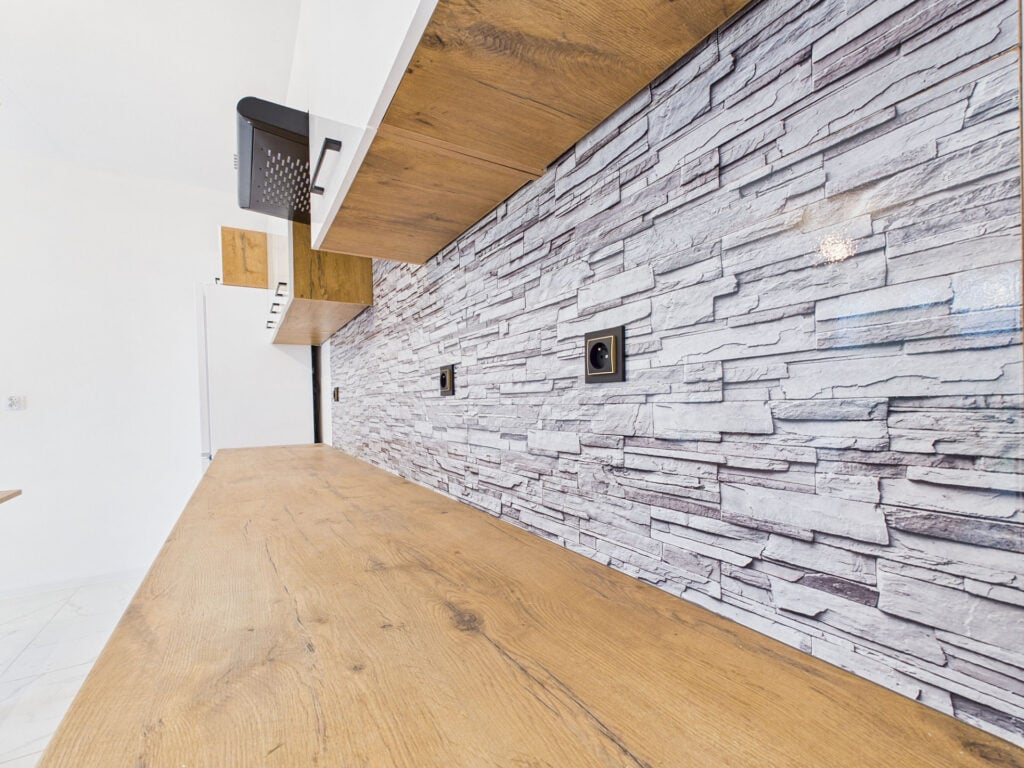 Kuchnia z drewnianym blatem i kamienną ścianą.