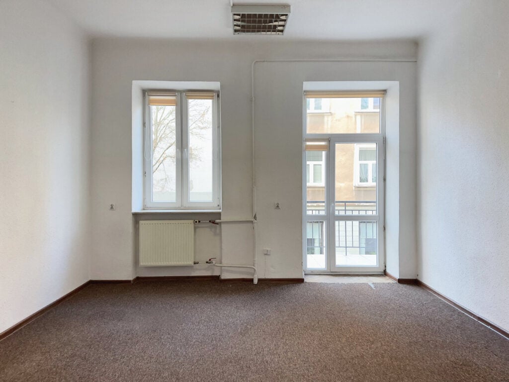 Puste biuro z oknami i grzejnikiem.