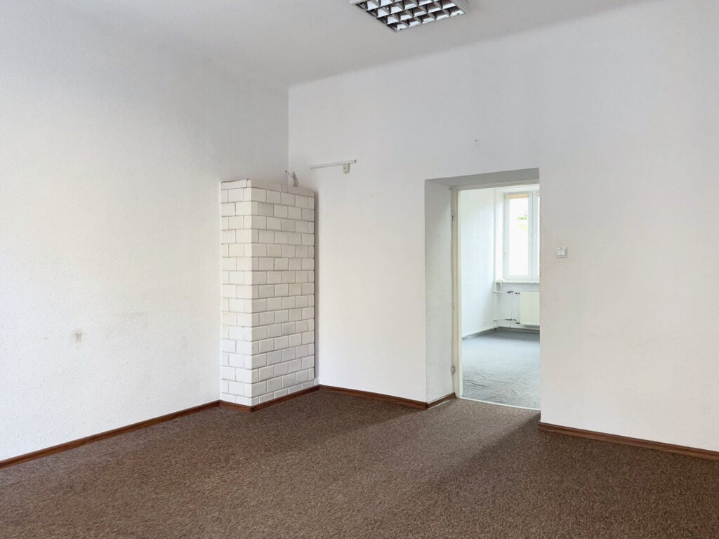 Puste pomieszczenie z białymi ścianami i drzwiami.