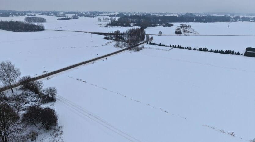 Zaśnieżone pola i droga widziane z lotu ptaka.