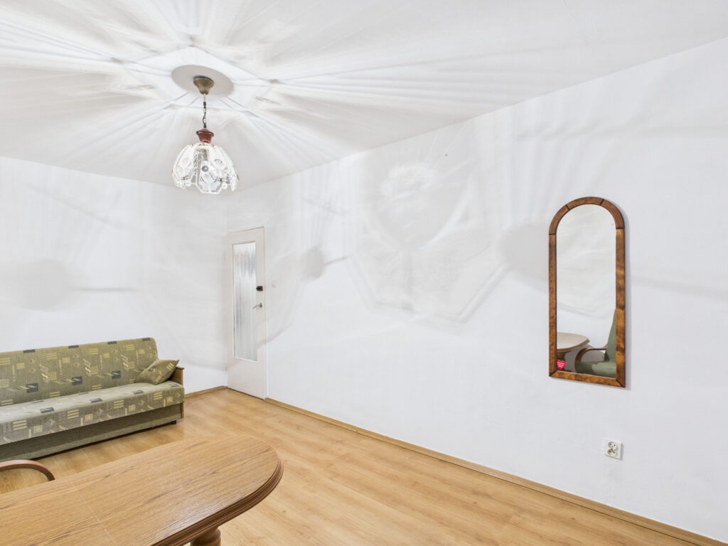 Pokój z sofą, lustrem i lampą.