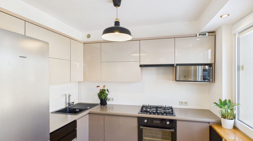 Nowoczesna kuchnia z białymi szafkami i sprzętem AGD.